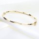 Złota bransoleta sztywna z efektem skręcenia i diamentowaniem